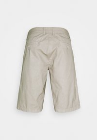 Shorts en coton beige avec un devant plat, deux poches arrière et des ourlets retroussés. Design simple sans motifs ni éléments visibles.