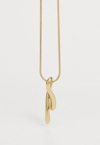 Collar con colgante de tono dorado y diseño alargado y retorcido. Superficie lisa con acabado brillante, colgando de una delgada cadena de serpiente.