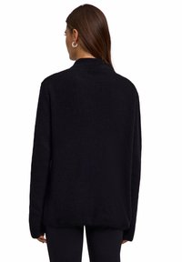 Maglione nero a coste con colletto alto e maniche lunghe. Texture morbida, vestibilità ampia e dettagli di cucitura minimi. Ideale per sovrapposizioni.