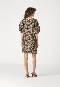 Haljina s leopard uzorkom s napuhanim kratkim rukavima, s okruglim izrezom i ravnim rubom. Izrađena od lagane tkanine.