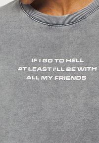 Szara bluza z prążkowanym, okrągłym dekoltem. Na froncie wyraźny biały napis: "JEŚLI TRAFIĘ DO PIEKŁA, PRZYNAJMNIEJ BĘDĘ ZE WSZYSTKIMI MOIMI PRZYJACIÓŁMI."