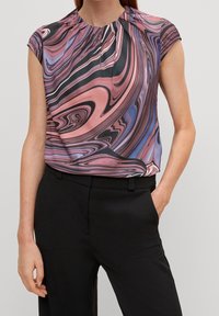 Kurzärmlige Bluse in einem mehrfarbigen Wirbelmuster aus Pink, Lila und Schwarz. Verfügt über einen plissierten Ausschnitt und eine lässige Passform. Kombiniert mit schwarzen Hosen.
