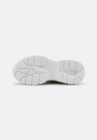 Suola di scarpa atletica bianca con profondi motivi di battistrada e gomma testurizzata. Superficie liscia con una leggera curvatura nel tallone.