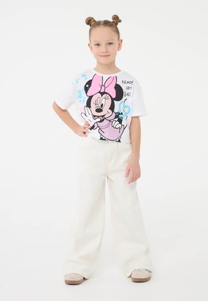 T-shirt bianca con una grafica colorata di Topolino con dettagli rosa, abbinata a pantaloni ampi color crema e scarpe beige.