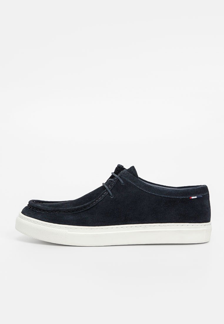 Marineblauwe suède schoenen met een witte rubberen zool, ronde neus en een minimalistisch vetersysteem. Met gestikte details en een klein merkaccent.