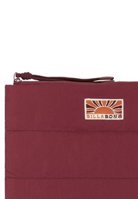 Borsetta marrone creata in un tessuto testurizzato, con una cerniera superiore e una toppa con logo intrecciato che presenta un design di sole in arancione e giallo.
