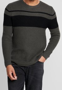 Strickpullover mit abwechselnden grauen und schwarzen horizontalen Streifen, rundem Ausschnitt, gerippten Ärmelbündchen und einer strukturierten Oberfläche.