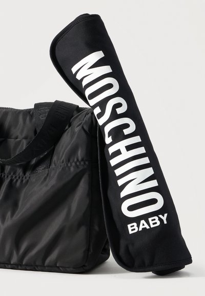 Μαύρη καπιτονέ τσάντα ώμου με φαρδιά ράβδο ώμου δίπλα σε μαύρο κάλυμμα χειρολαβής καροτσιού με μεγάλο λευκό κείμενο "MOSCHINO BABY".