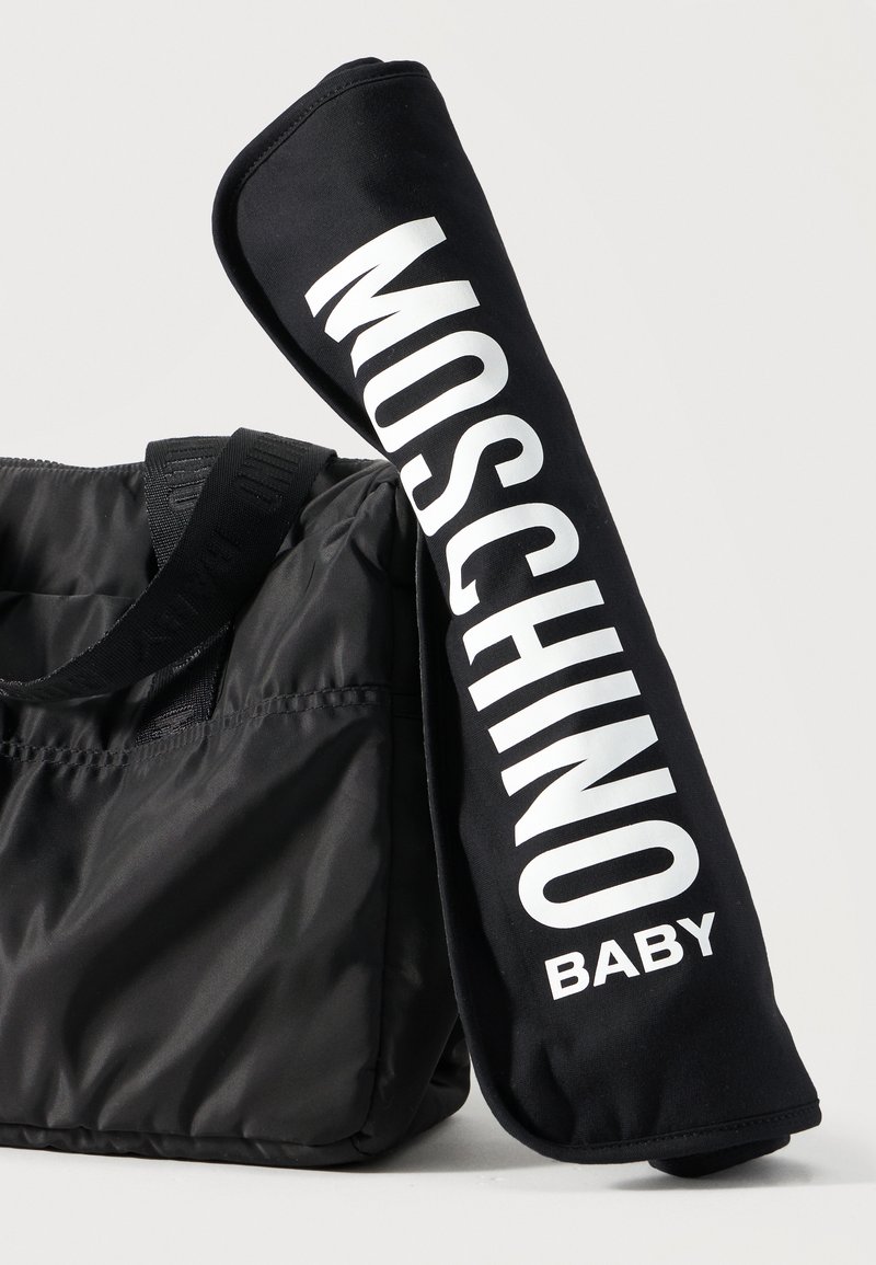 Black quilted tote bag with wide shoulder strap next to black stroller handle cover with large white "MOSCHINO BABY" text.