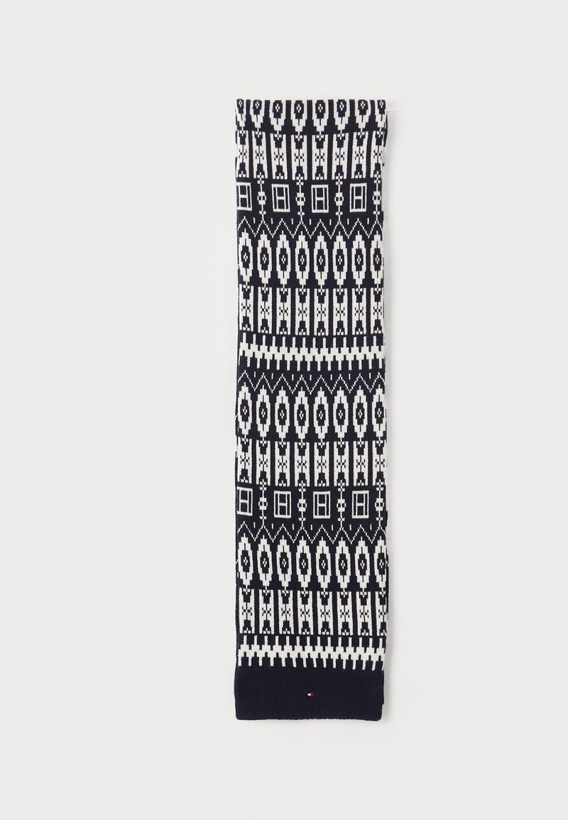 Écharpe en tricot avec un motif géométrique bleu marine et blanc, présentant des formes allongées et des accents carrés, terminée par un bord tricoté uni.