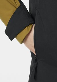 Černá vrchní bunda s hladkou texturou, s kapsou na zip a kontrastní olivově zelenou látkou na manžetách.