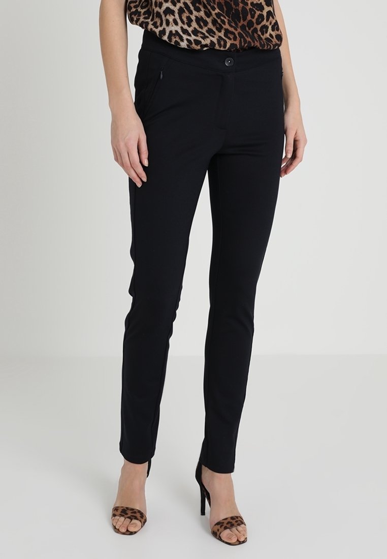 Black stretch pants made of soft fabric, featuring a slim fit, a button closure, and side pockets, worn with leopard print heels.