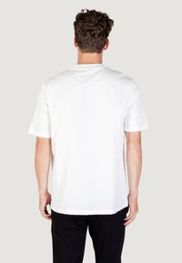 Camiseta de algodón blanca con cuello redondo y mangas cortas. Textura suave, corte relajado y un diseño liso sin patrones ni detalles visibles.
