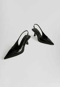 Črne patentne slingback čevlje s koničastim prstom in zmerno peto, ki imajo gladko površino in minimalističen dizajn.