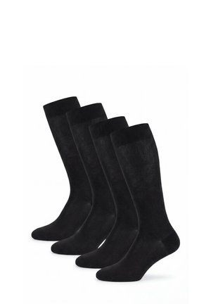 Vier Paar schwarze knielange Feinsocken, aufrecht in versetzter Reihe auf weißem Hintergrund angeordnet.