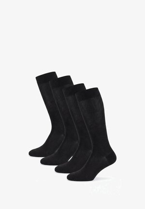 Vier Paar schwarze knielange Feinsocken, aufrecht in versetzter Reihe auf weißem Hintergrund angeordnet.