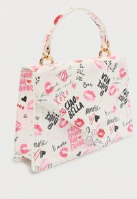 Bolso blanco hecho de material brillante, con estampados de labios en rosa y rojo, texto manuscrito y un asa con herrajes dorados.