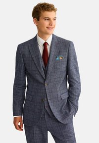 Zweiteiliger Anzug aus strukturiertem Marineblauem Stoff mit Karomuster. Er verfügt über ein einreihiges Sakko, braune Knöpfe und ein Einstecktuch.