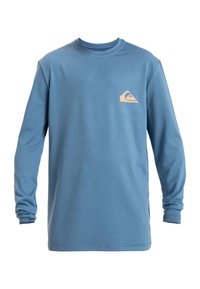 Blå långärmad t-shirt i mjukt tyg, med en liten beige logotyp på bröstet och detaljerad design på ärmsluten.