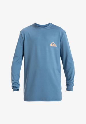 Sininen pitkähihaiset t-paita, joka on valmistettu sileästä kankaasta. Paidassa on pieni beige logo rinnassa ja yksityiskohtainen muotoilu hiharesoreissa.