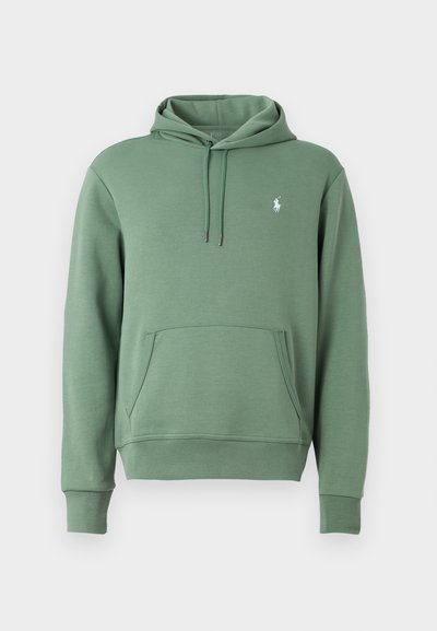 Zelena kapuca iz mehkega materiala, z kenguru žepom in kapuco na vrvico. Diskretna zaščitna znamka na prsih. Klasičen kroj z rebrastimi manšetami.