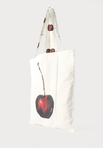 Sac fourre-tout en tissu blanc avec un grand motif de cerise rouge sur le corps et de plus petits imprimés de cerises sur les anses.