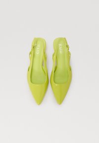 Talons aiguilles slingback vert citron avec bouts pointus, en simili cuir lisse et détails découpés. La marque apparaît sur la semelle intérieure.