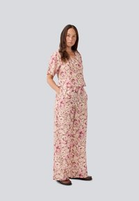 Set due pezzi con motivo floreale rosa, composto da una maglietta a maniche corte con scollatura a V e pantaloni a gamba larga con tasche, realizzato in tessuto leggero.