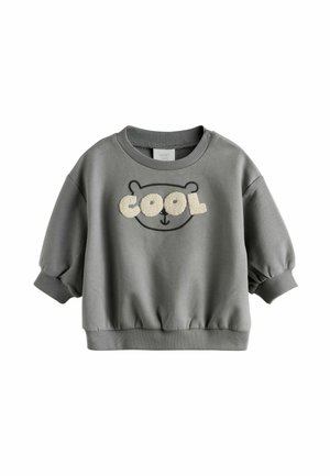 Sweatshirt gris avec un col rond, des manches bouffantes, des poignets et un bas à côtes. Présente un visage d'ours et le mot "COOL" en broderie crème.