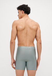 Grå boxershorts med elastisk midjebånd med "UNUR"-merke. Glatt, tettsittende design med en subtil tekstur. Ingen ytterligere detaljer synlige.