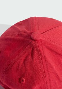 Červená čiapka so pevným textilným vzorom, zaoblený tvar, šesťpanelový dizajn a horný gombík v strede. Viditeľné šité švy.