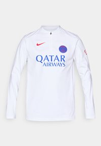 Bijela sportska majica dugih rukava s crvenim detaljima, koja ima ovratnik s pola zatvarača, plavi logo "QATAR AIRWAYS" i okrugli grb momčadi na prsima.