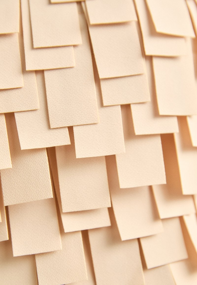Peach-colored texture made of overlapping, rectangular paper layers with a subtle, matte finish. The arrangement creates a three-dimensional effect.