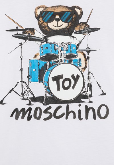Camiseta blanca con un oso con gafas de sol tocando un set de batería azul. El texto dice "TOY Moschino" en negro. Diseño gráfico audaz.