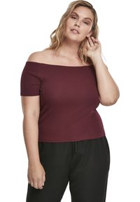 Burgundské tričko s odhalenými rameny vyrobené z žebrované tkaniny, s krátkými rukávy, upnutým střihem a rovně střiženým lemem. Spárováno s černými kalhotami.