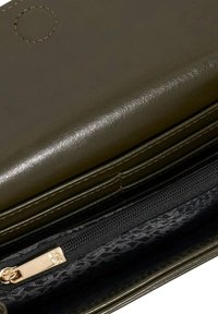 Olive green leather wallet with smooth texture, zippered compartment, and a patterned interior fabric in black and gray. Accented with gold hardware.