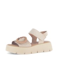Beige Wildleder-Sandalen mit einer dicken cremefarbenen Sohle, ausgestattet mit einem dekorativen, mit Perlen besetzten Kreisdétails und einem Klettverschluss am Knöchel für einen sicheren Sitz.