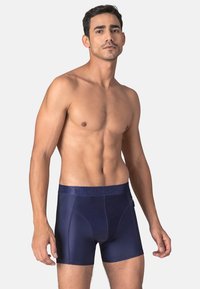 Navy blue boxer shorts featuring a smooth, glossy texture, a wide waistband with branding, and a fitted design emphasizing shape and comfort.