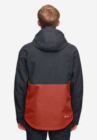 Techniczna kurtka na zewnątrz w kolorze czarnym i czerwonym. Posiada kaptur, fakturowany materiał oraz wzór w blokach kolorowych z dłuższym tylnym dołem.