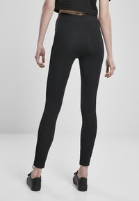 Sorte leggings med en jevn tekstur, høy livlinje, og et sidepanel med en utskåret leopardmønsterdesign.