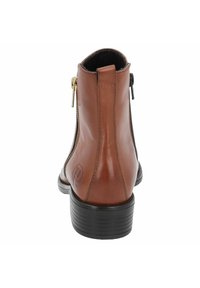Botín de cuero marrón hasta el tobillo con un tacón negro, cierres laterales con cremallera y un detalle de logo en el lado exterior. Textura suave y forma estilizada.