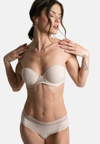 Soutien-gorge sans bretelles beige et culotte assortie en tissu lisse, avec des détails discrets, des bandes élastiques et des coques conçues pour le soutien et la forme.