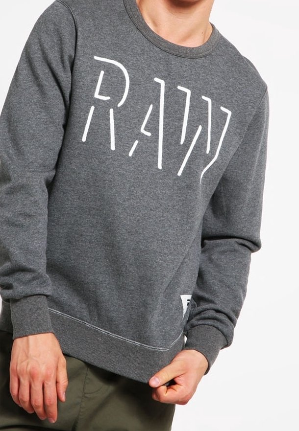 Sudadera gris con cuello redondo, que presenta un logotipo blanco de "RAW". Fabricada con material suave y con puños y dobladillo acanalados.