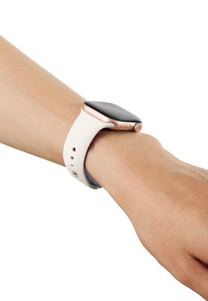 Reloj inteligente con pantalla negra y correa beige, llevado en la muñeca sobre fondo blanco.