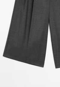 Grijze wijde broek gemaakt van een gestructureerde stof, met een hoge taille en subtiele plooien voor extra vorm.