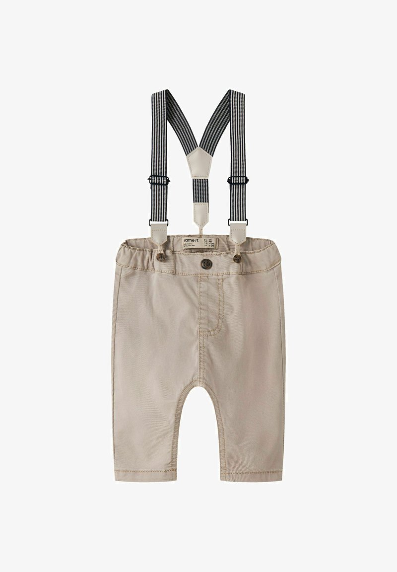 Pantalon beige pour bébé avec taille élastique, trois boutons et bretelles réglables à rayures noires et blanches attachées.
