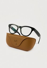 Gafas de plástico negro con lentes transparentes, de forma redondeada, colocadas sobre un estuche de cuero marrón con textura suave y detalle de logo.