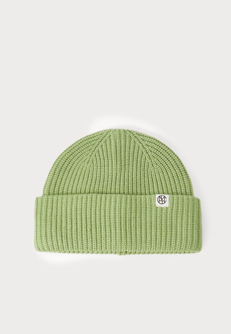 Light green knit beanie with a ribbed texture, featuring a turned-up cuff and a small logo label on the side. Soft and stretchy design.
