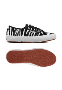 Sneakers in tela bianca e nera con un motivo a strisce, suola in gomma con parte inferiore rossa testurizzata e lacci neri. Logo del marchio sul lato.