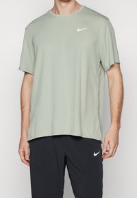 Světlá zelená triko Nike vyrobené z měkké tkaniny, s kulatým výstřihem, krátkými rukávy a malým bílým logem na levé hrudi.